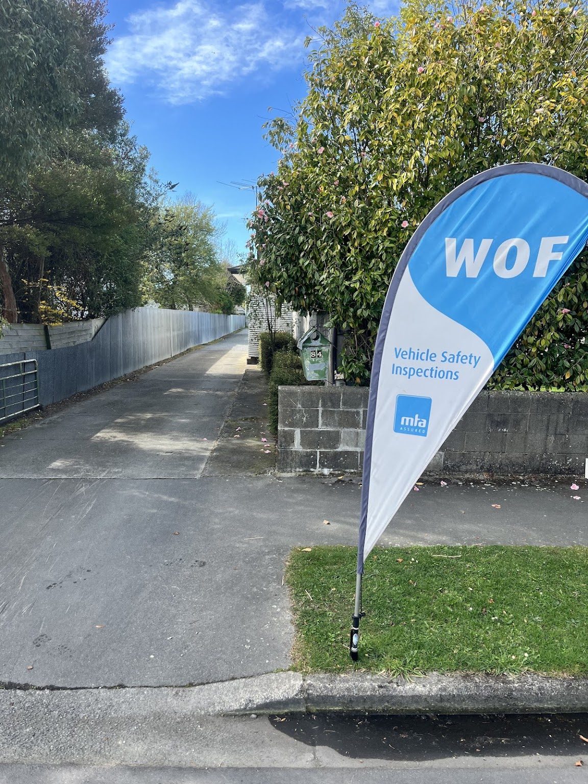 The West Belt Motors WOF vehicle safety inspections flag at the driveway entrance, 84 West Belt, Rangiora